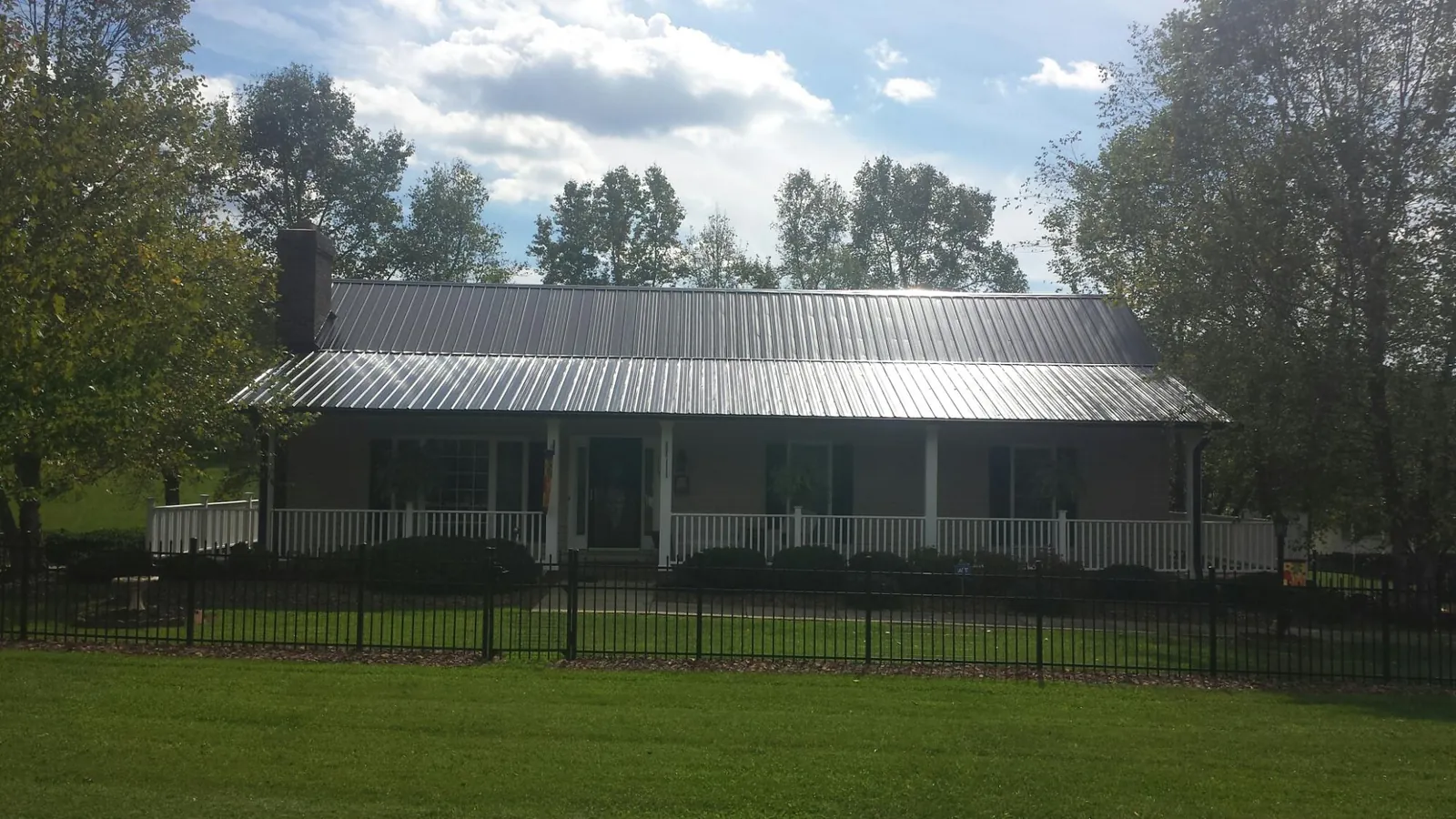 Gray metal roof on a brick ranch with a full width front porch — Gutter Guard Installation work by our crew in Lamar